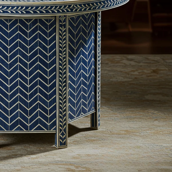 Close-up of a blue and white patterned table leg on a wooden floor.